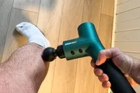 A person uses the Ekrin B37 Massage Gun on their leg