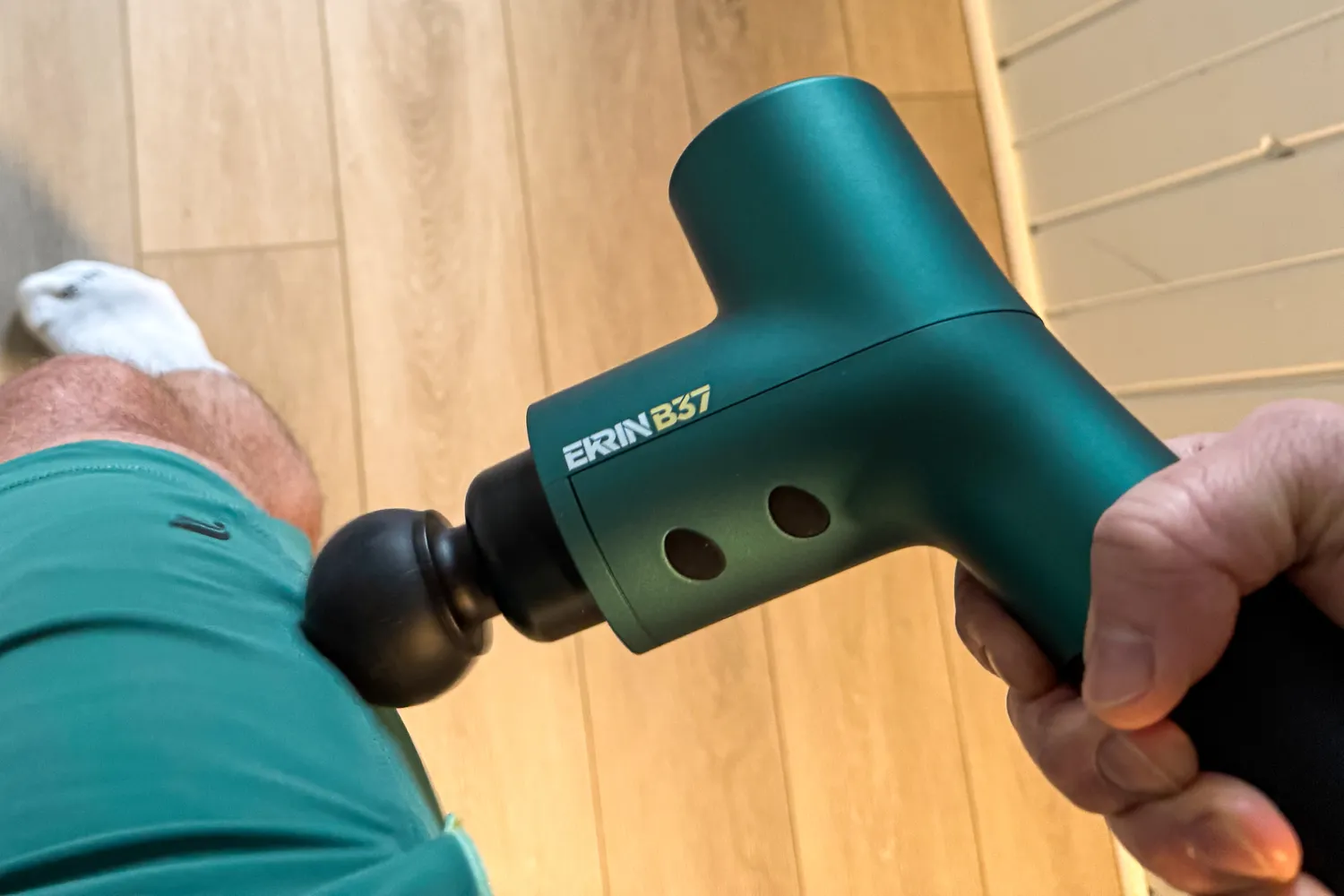 A person uses the Ekrin B37 Massage Gun on their hip