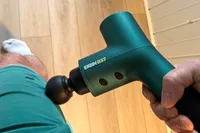 A person uses the Ekrin B37 Massage Gun on their hip