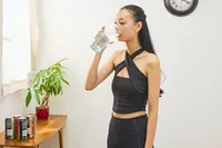 A person drinks LMNT Sparkling Electrolyte Water from a glass