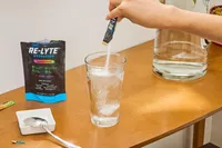 A person pours REDMOND Re-Lyte Hydration Electrolyte Mix into a glass of water