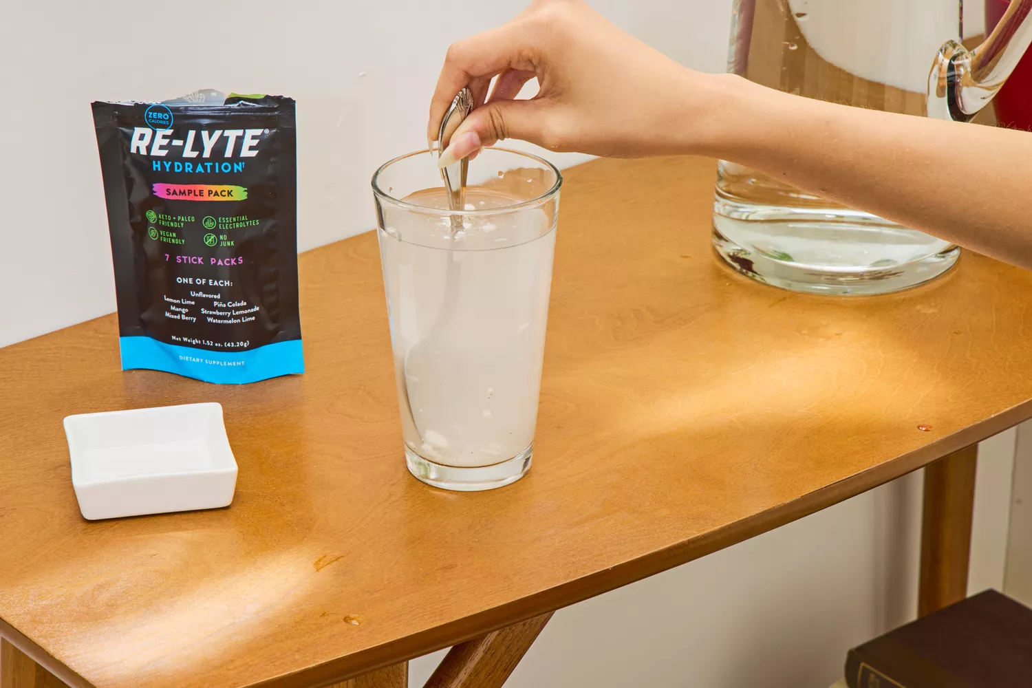 A person stirs REDMOND Re-Lyte Hydration Electrolyte Mix into water