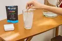 A person stirs REDMOND Re-Lyte Hydration Electrolyte Mix into water
