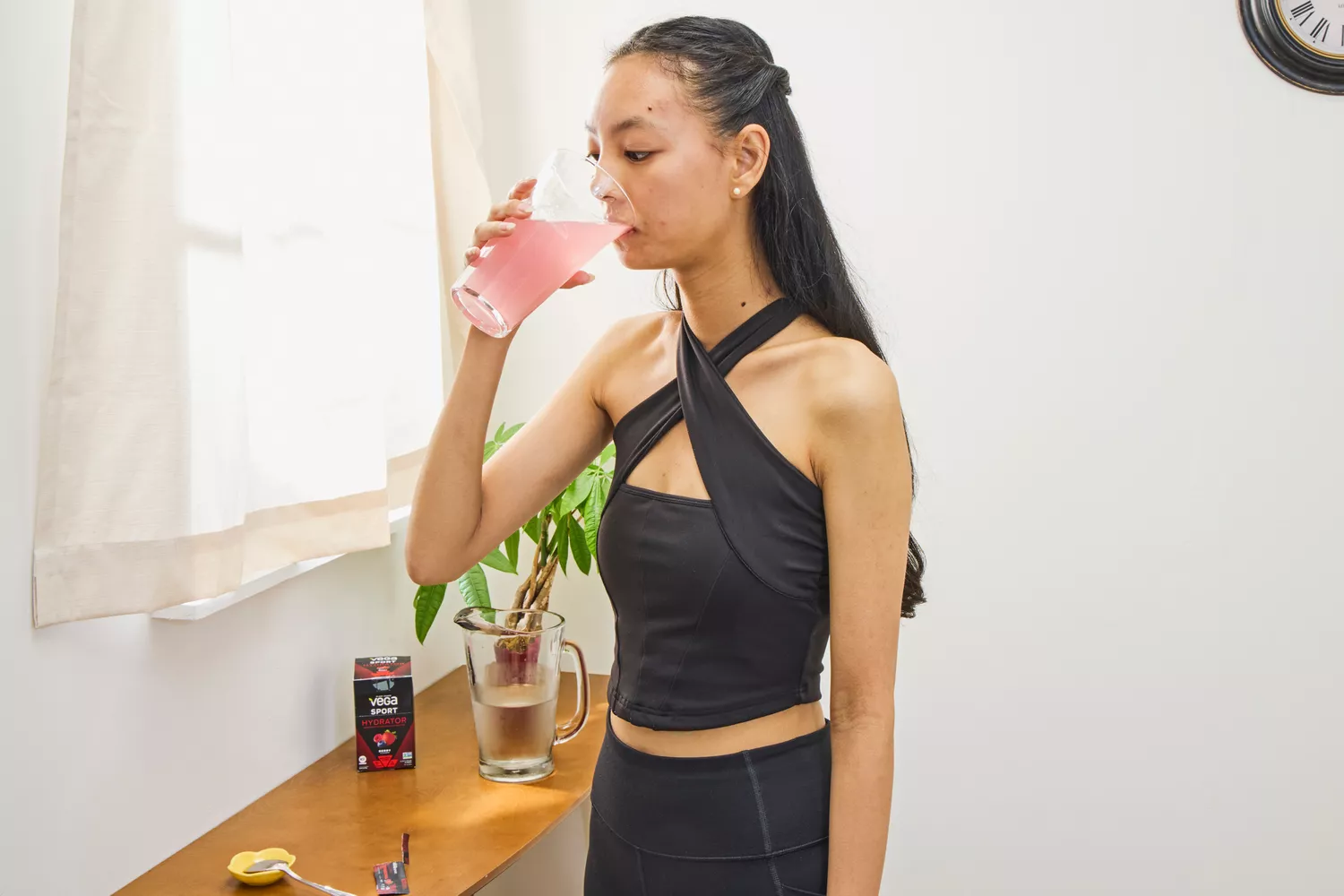 A person pours Vega Sport Electrolyte Hydrator into a glass of water