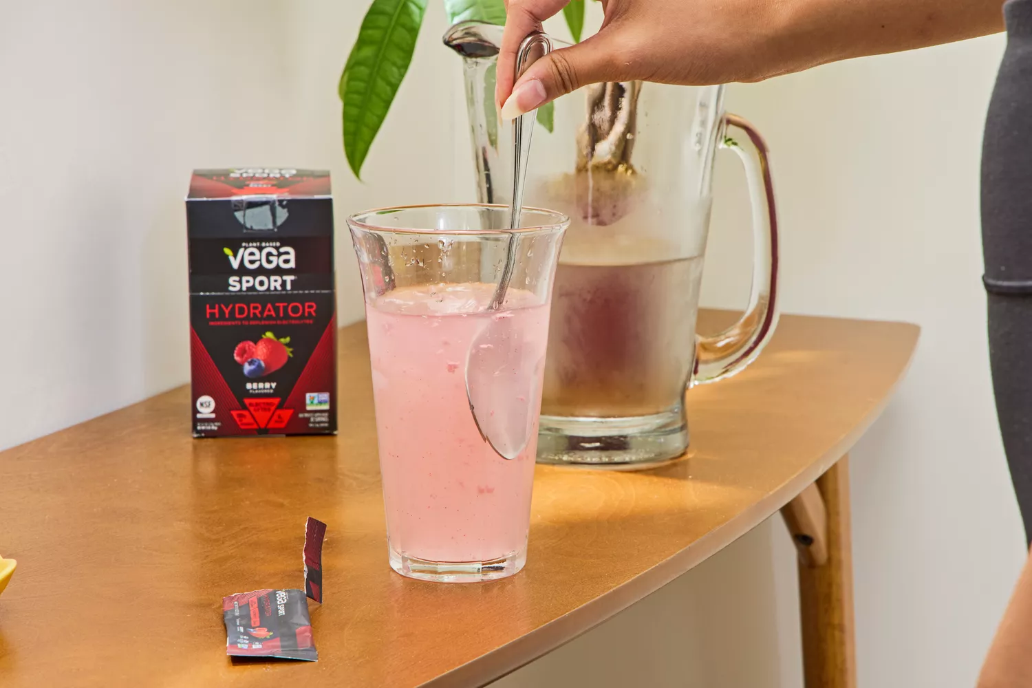 A person stirs Vega Sport Electrolyte Hydrator into a glass of water