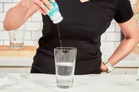 A person adding Buoy Electrolyte Drops to water