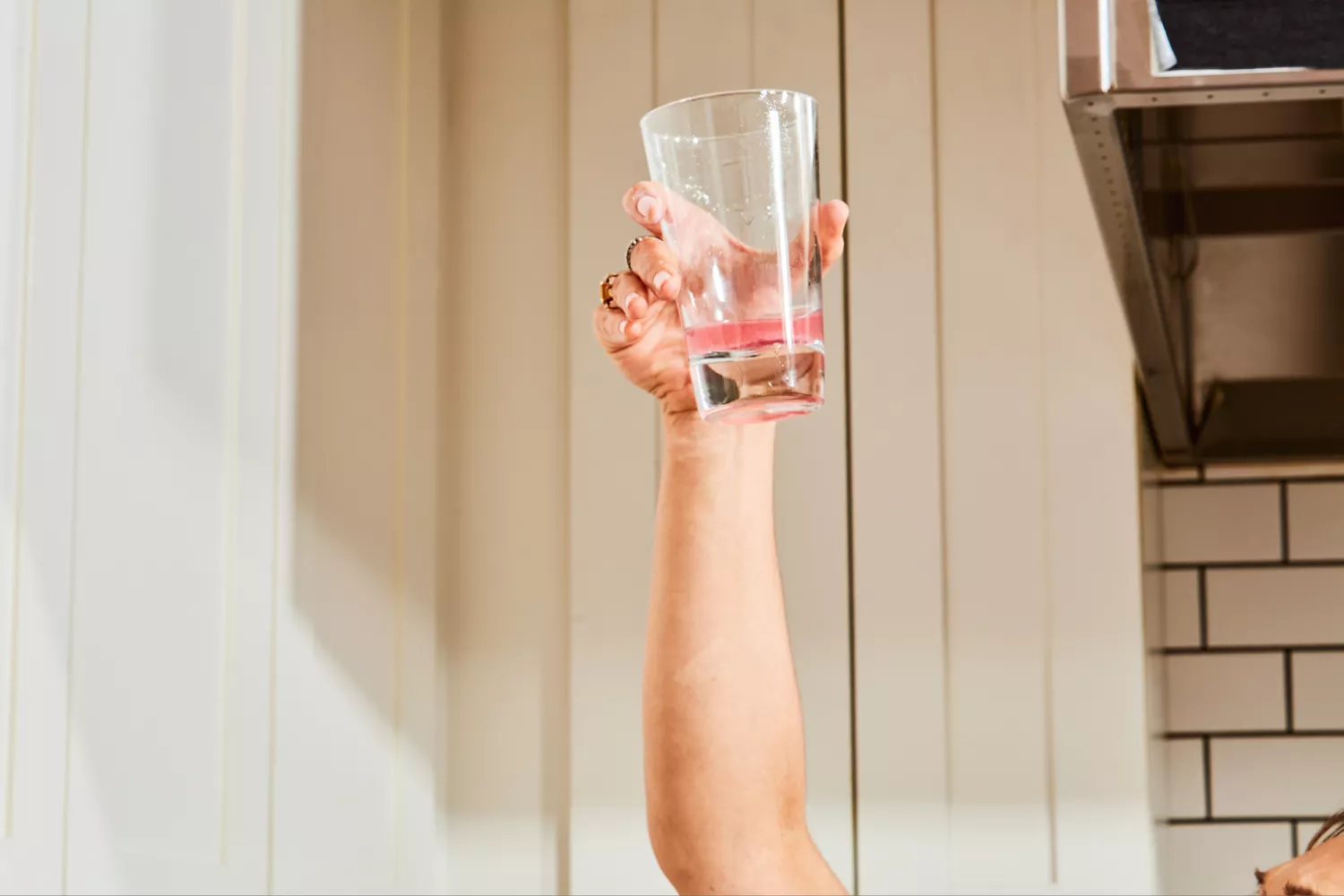 An arm listing up a glass of Gnarly Nutrition Hydrate Electrolyte Powder mixed with water