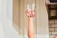 An arm listing up a glass of Gnarly Nutrition Hydrate Electrolyte Powder mixed with water