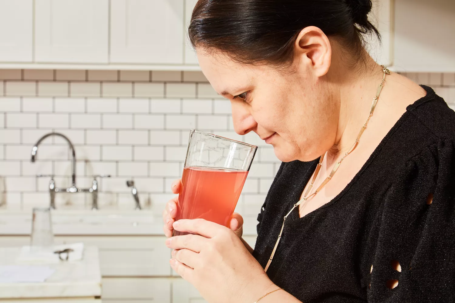 A person sniffing a glass containing a beverage made with Hydrant Hydrate Hydration Drink Mix