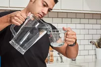 A person adding water into a measuring cup to later mix with Kaged Hydra Charge