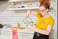 A person pouring water into a measuring cup to test Tailwind Nutrition Caffeinated Endurance Fuel
