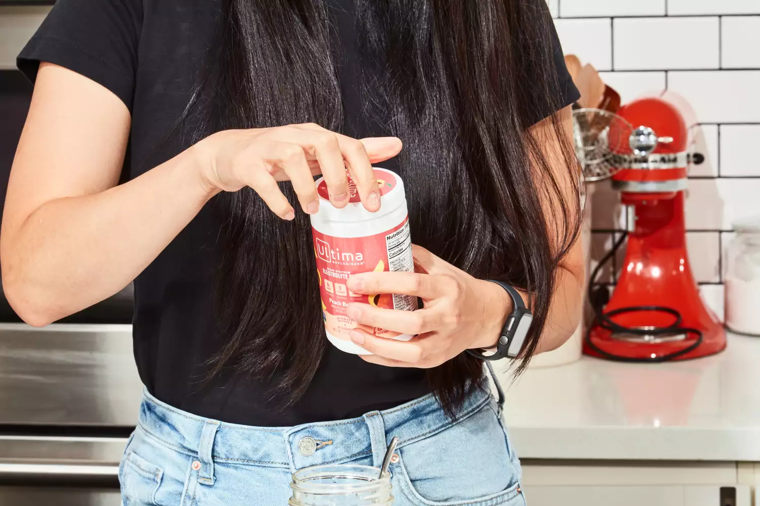 A person opening a Ultima Replenisher Electrolyte Hydration Powder jar