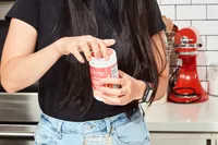 A person opening a Ultima Replenisher Electrolyte Hydration Powder jar