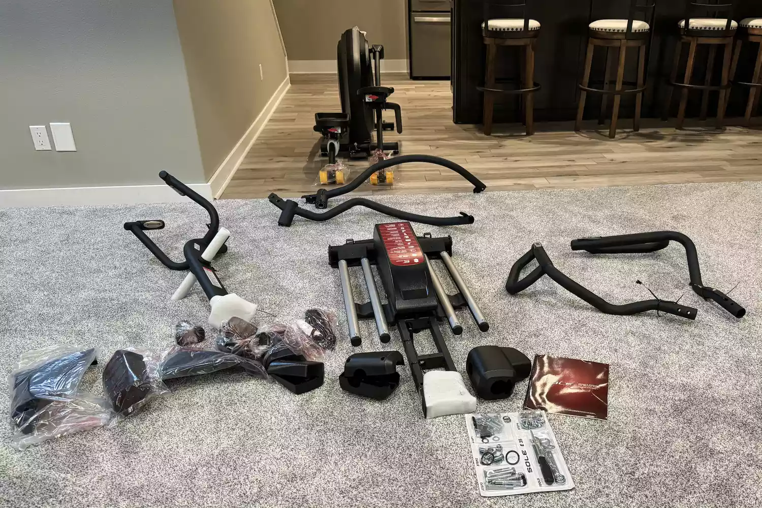 The parts of the Sole E35 Elliptical on a carpet