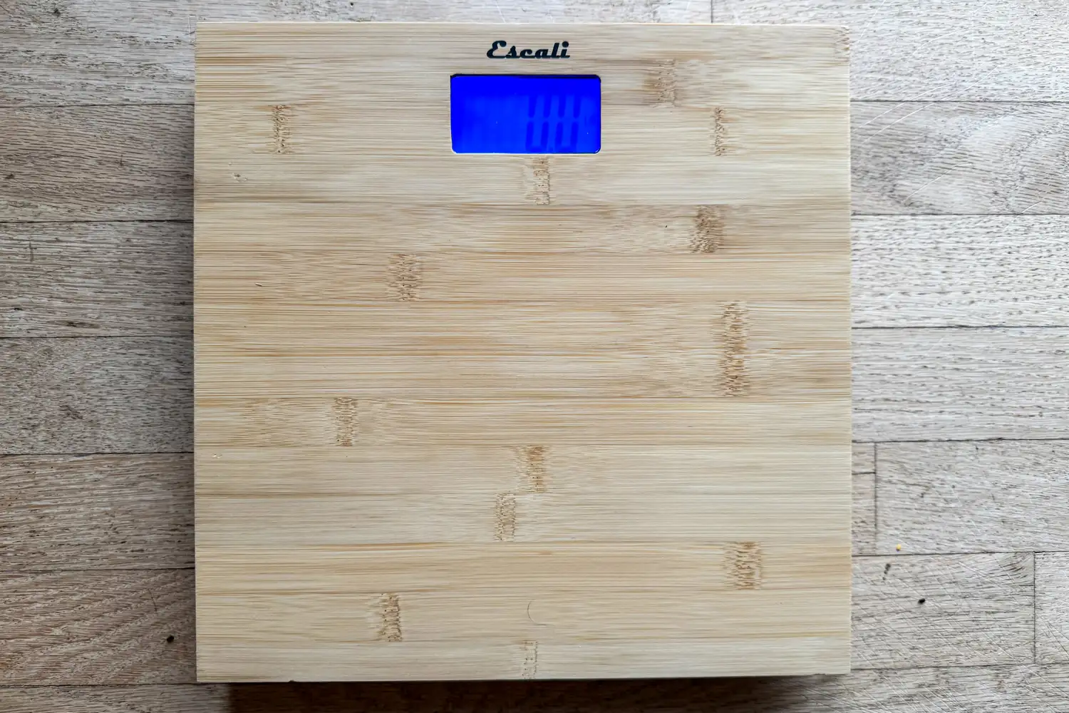 The Escali Bamboo Digital Electronic Bathroom Scale on a wooden floor