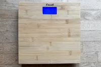 The Escali Bamboo Digital Electronic Bathroom Scale on a wooden floor
