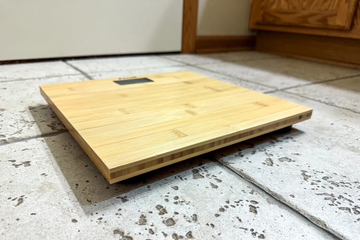 The Escali Bamboo Digital Electronic Bathroom Scale on a tile floor