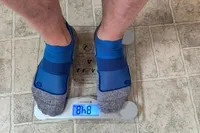 A person stands on the Etekcity EB4074C Digital Body Weight Scale in socks