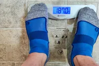A person stands on the Etekcity EB4074C Digital Body Weight Scale in socks