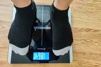 A person stands on the Etekcity ESF93 Smart Fitness Scale in socks