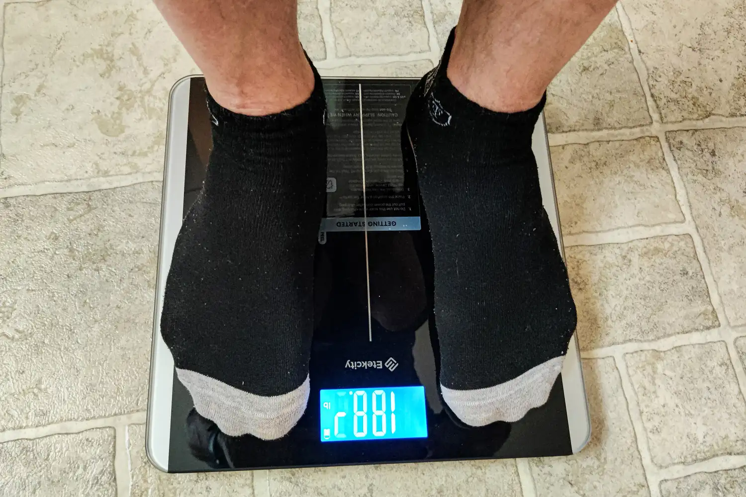 A person stands on the Etekcity ESF93 Smart Fitness Scale in socks