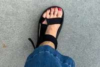 A person's foot wearing the FitFlop Women's GEN-FF Adjustable Webbing/Leather Back-Strap Sandal with jeans