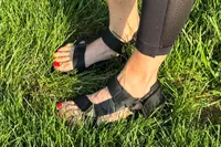 A person wearing FitFlop Women's GEN-FF Adjustable Webbing/Leather Back-Strap Sandals standing on grass