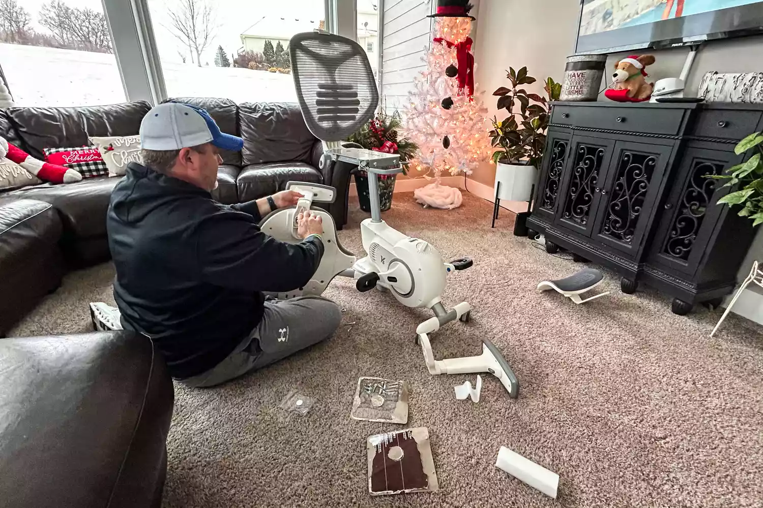 A person sitting on a carpet while assembling the Flexispot Deskbike V6 Pro