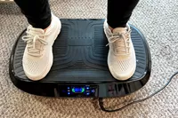 A person stands on the Flybird Mini Vibration Plate