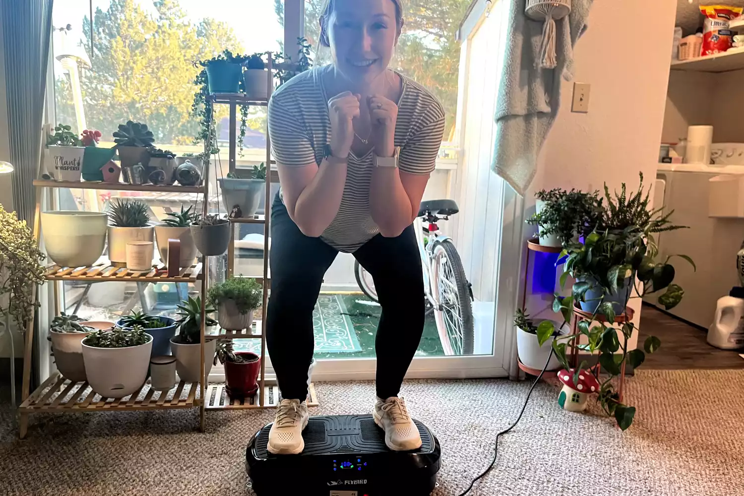 A person squats on top of the Flybird Mini Vibration Plate