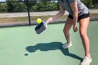 A person hits a pickleball using the GAMMA Airbender 10 Pickleball Paddle