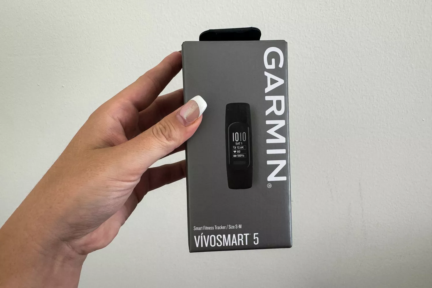 A person holds up the box for the Garmin vívosmart 5 Fitness Tracker