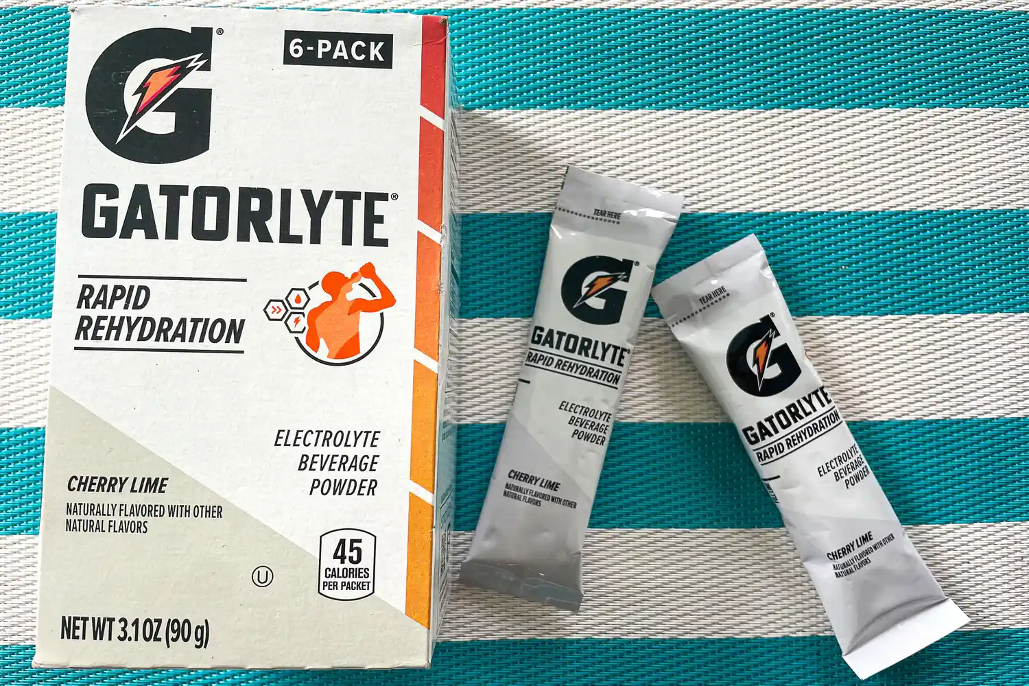 Gatorlyte Rapid Rehydration electrolyte powder packaging and two sachets on a striped surface