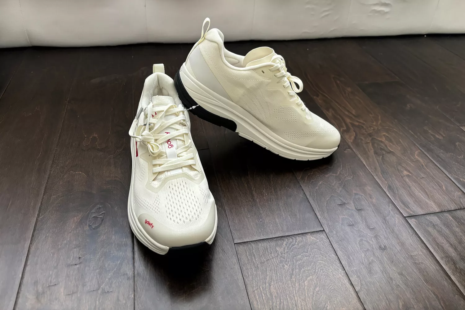 A pair of GDEFY Men's Lauff Athletic Shoes on a wooden floor