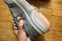 A person holds up the GDEFY Women's Ion Athletic Shoe
