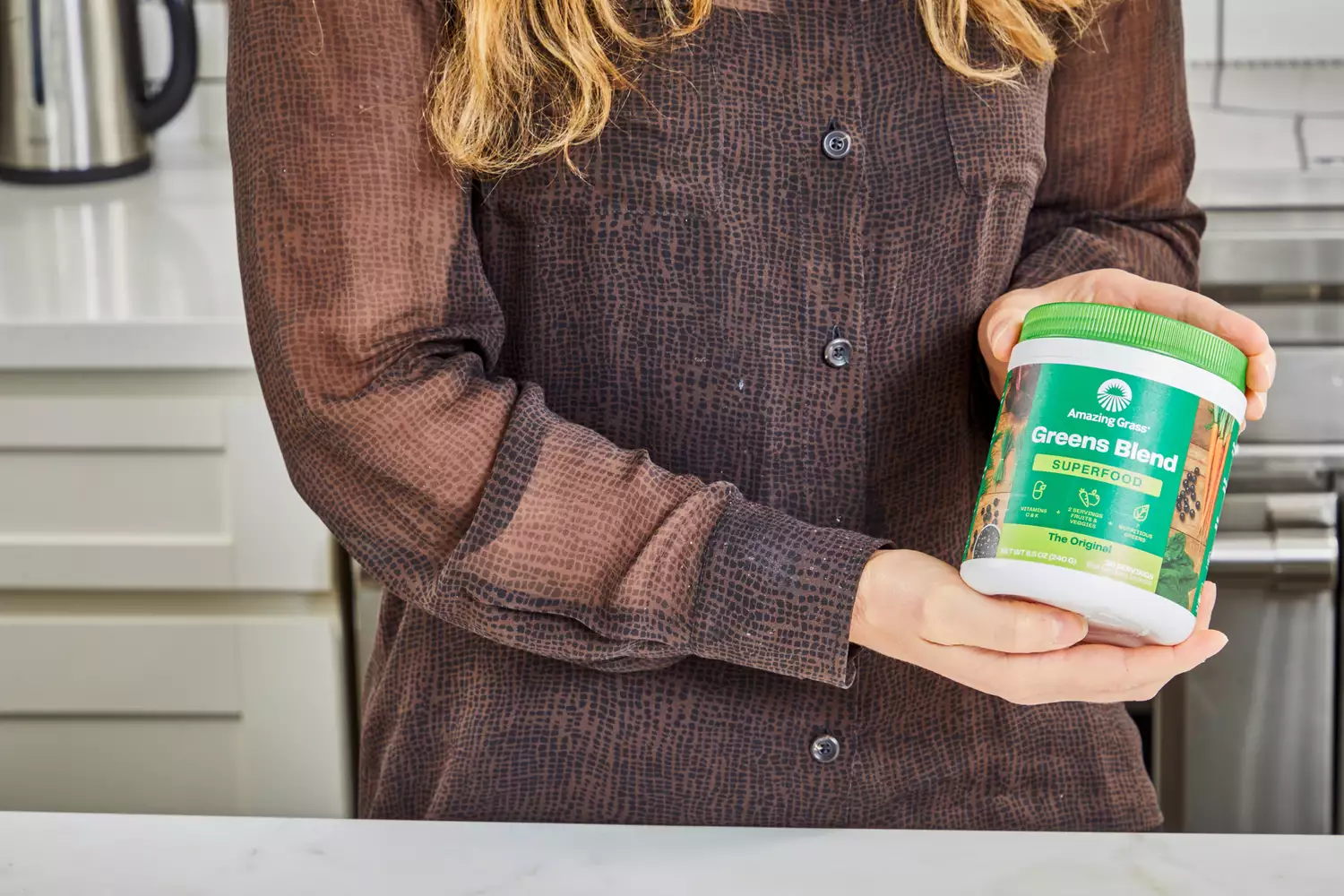 Person holding container of Amazing Grass Greens Blend