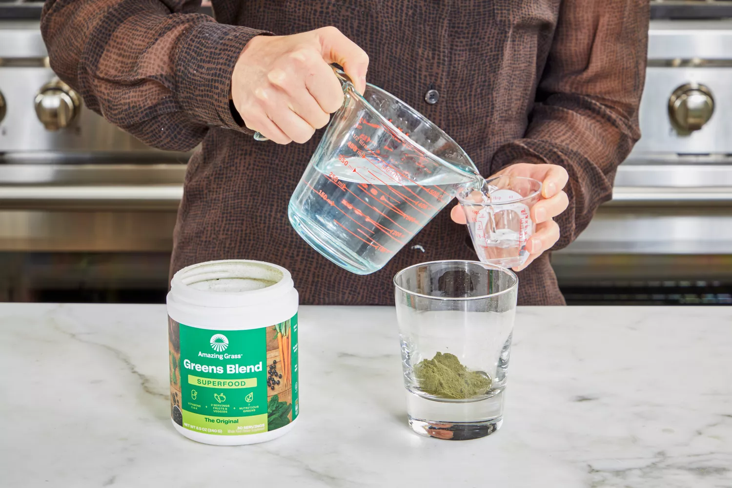 Person pouring water to mix with Amazing Grass Greens Blend Superfood