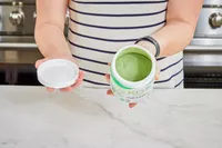 Person holding open container KOS Show Me the Greens Powder