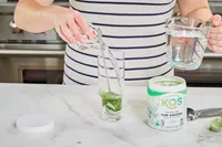 Person pouring water to KOS Show Me the Greens Powder 
