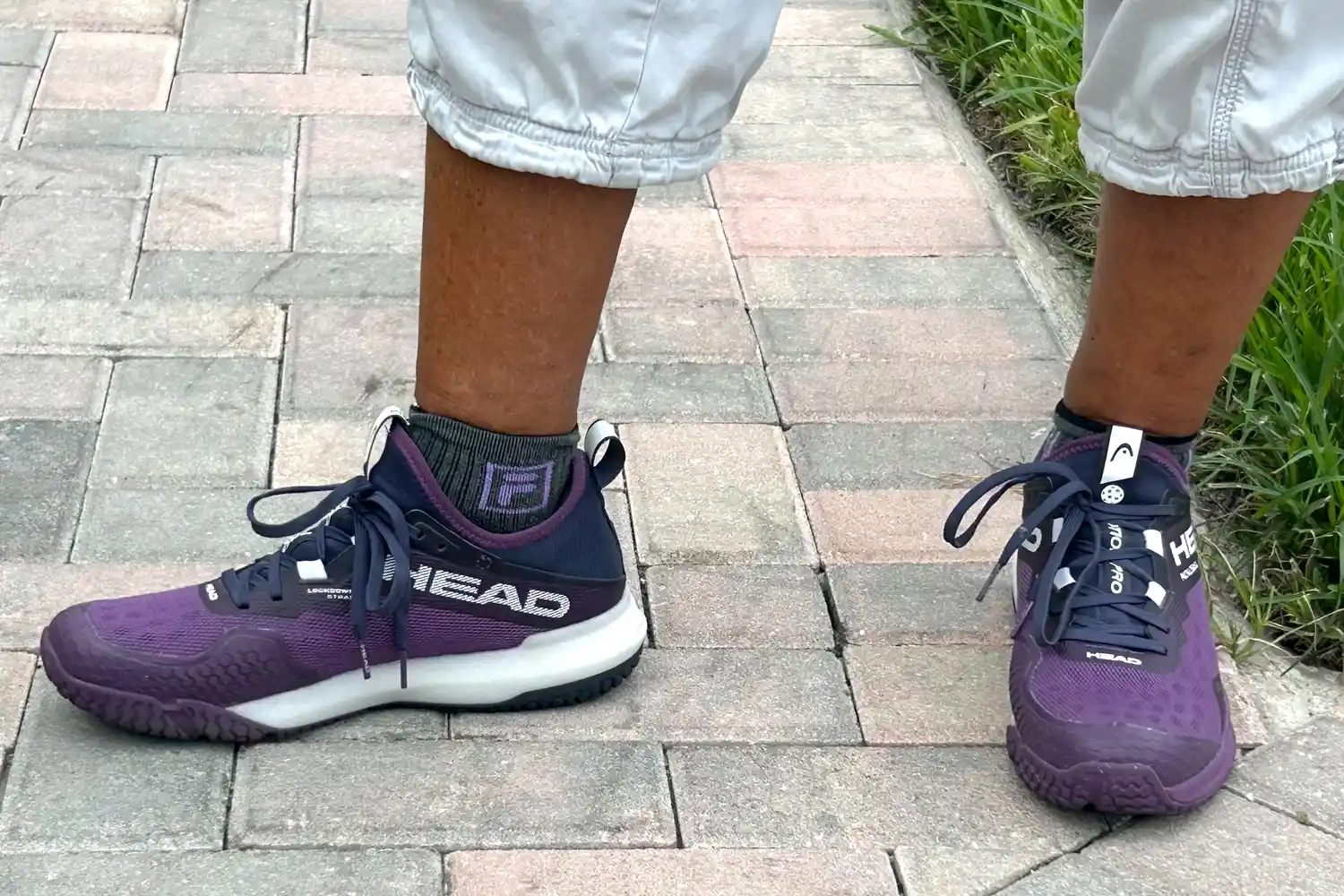 A person wears the HEAD Women's Motion Pro Pickleball Shoes outside on brick
