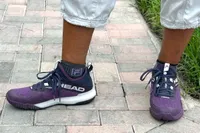 A person wears the HEAD Women's Motion Pro Pickleball Shoes outside on brick