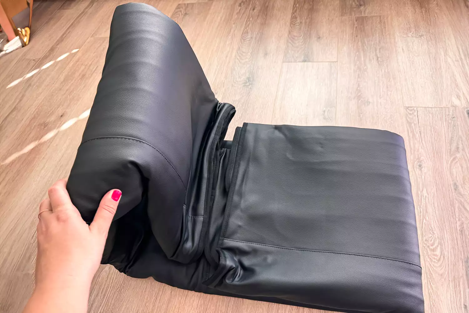 A hand unfolding the HEALiX-Z Sauna Blanket