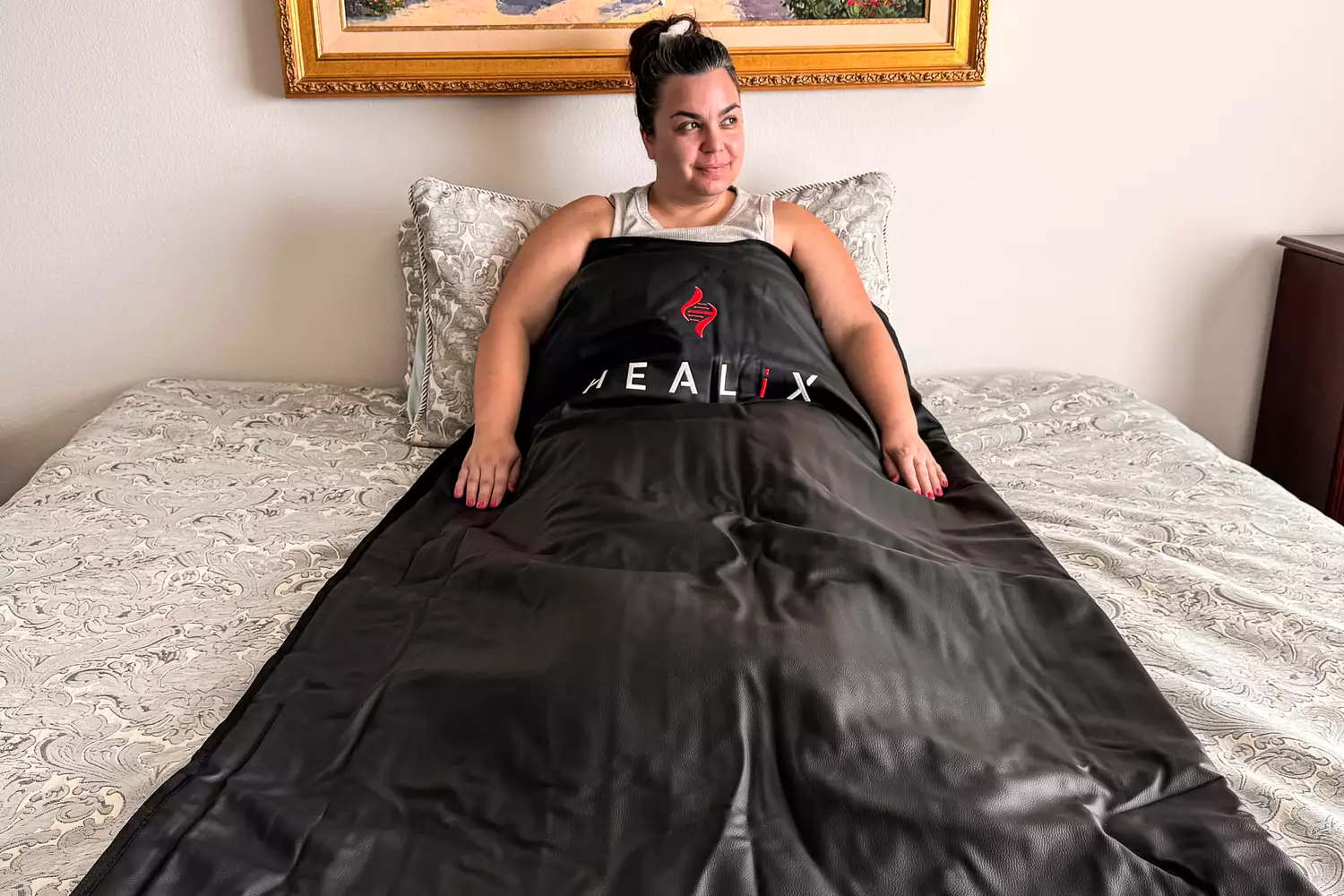 A person using the HEALiX-Z Sauna Blanket on a bed