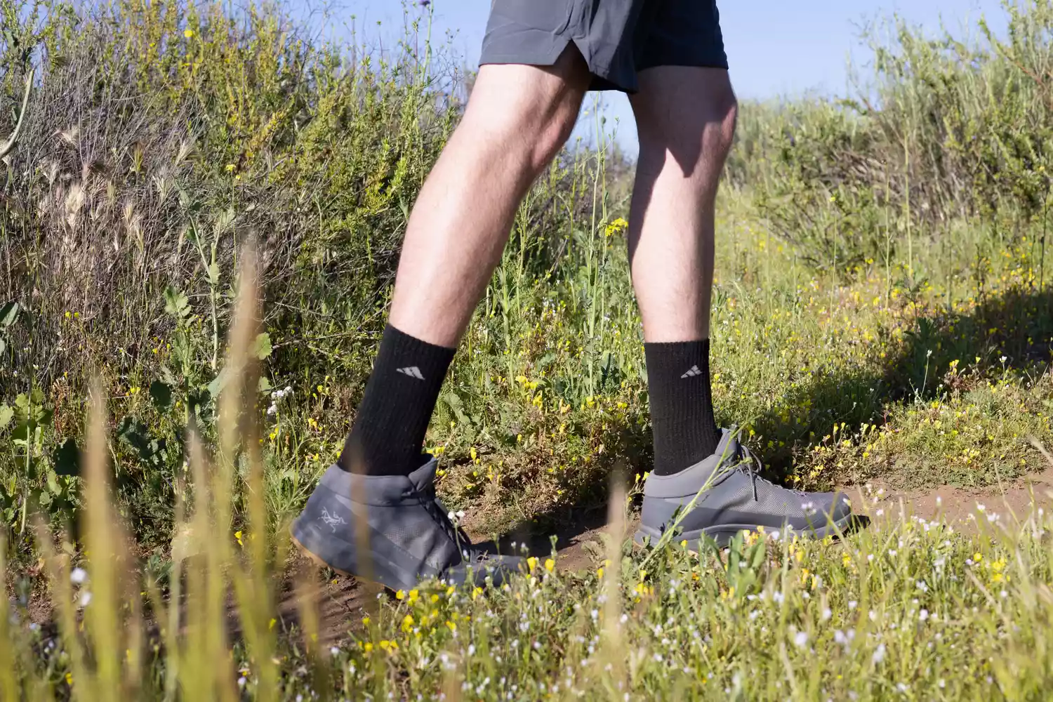 person walking on a grassy path wearing Arc'teryx Aerios FL 2 Mid GTX Hiking Shoe