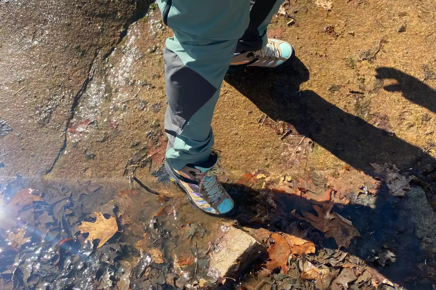 Feet wearing Merrell Men's Moab 3 Mid Hiking Boot alongside creek