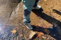 Feet wearing Merrell Men's Moab 3 Mid Hiking Boot alongside creek