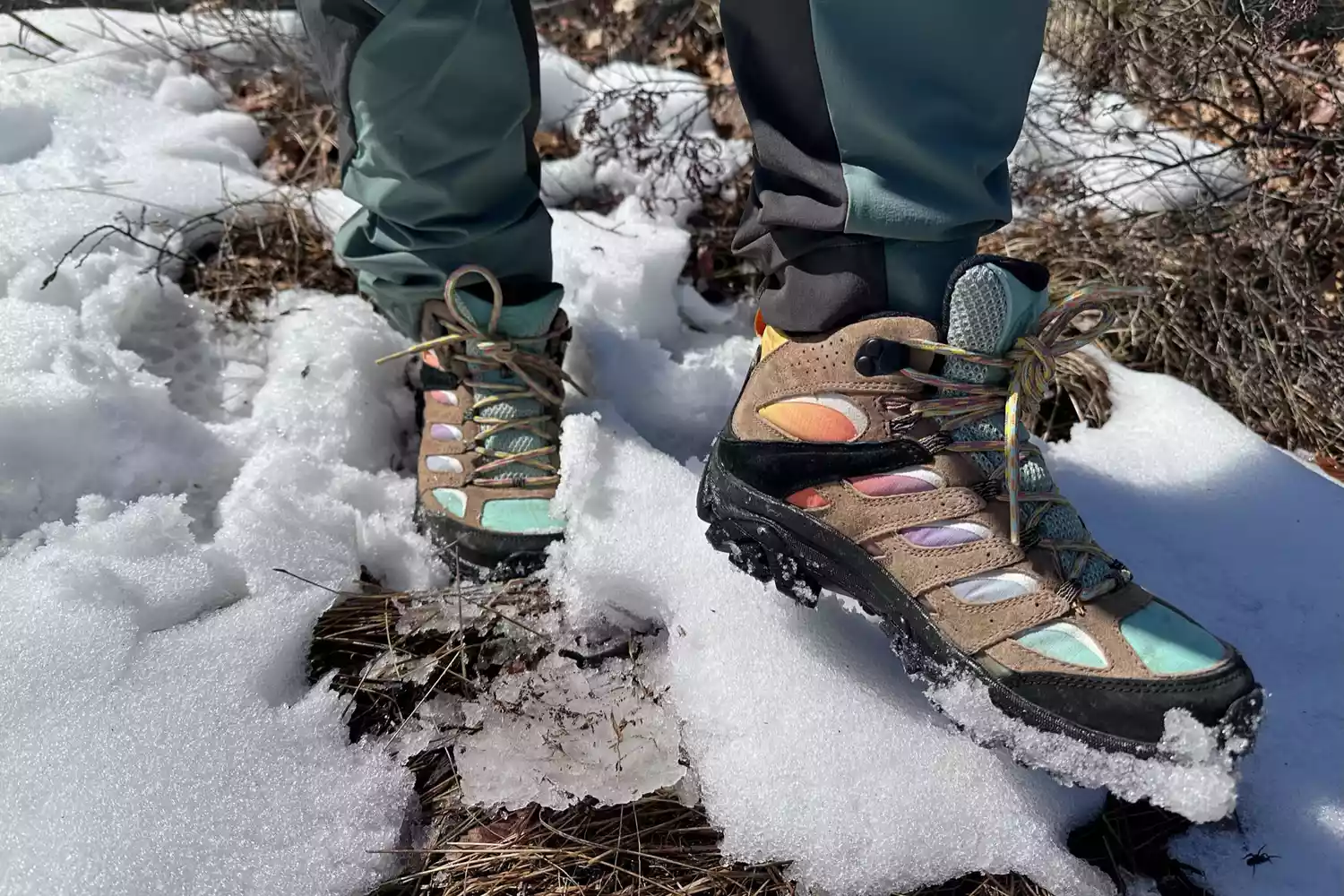Feet wearing Merrell Men's Moab 3 Mid Hiking Boot and standing in snow