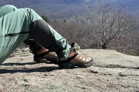 Legs and feet in Merrell Men's Moab 3 Mid Hiking Boot on rock overlooking valley