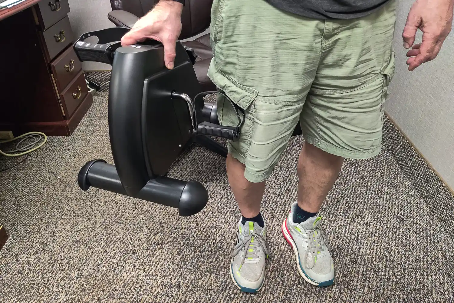 A person lifts the Himaly Mini Exercise Bike by the vertical base