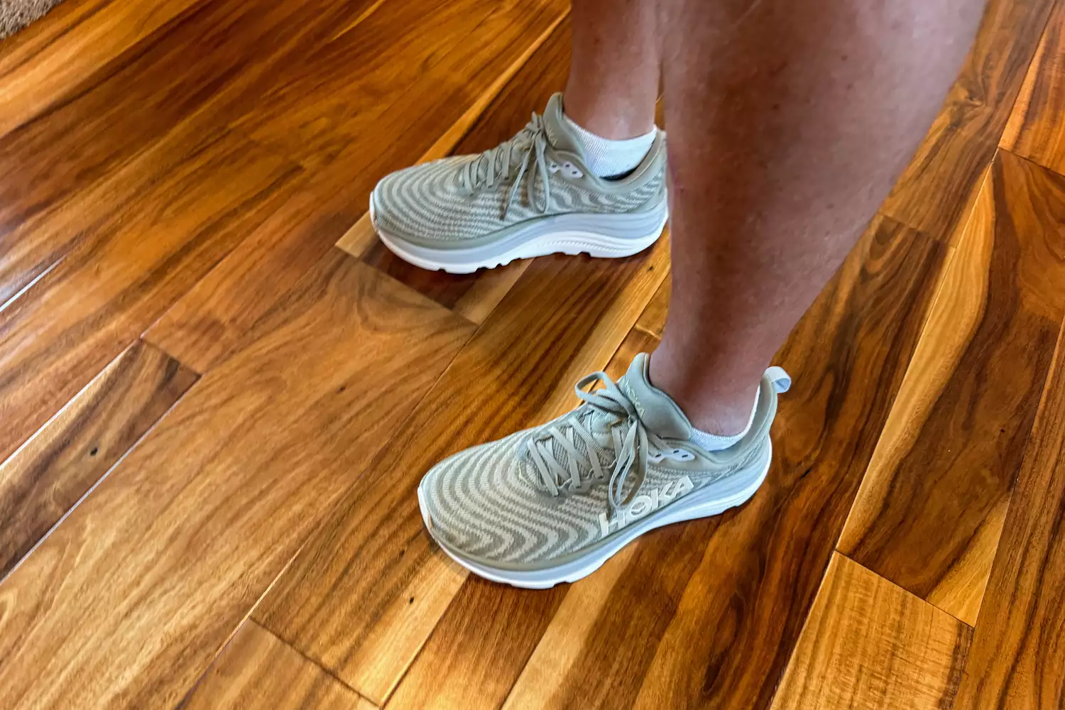 A person stands on a hardwood floor while wearing the Hoka's Men's Gaviota 5 Running Shoes